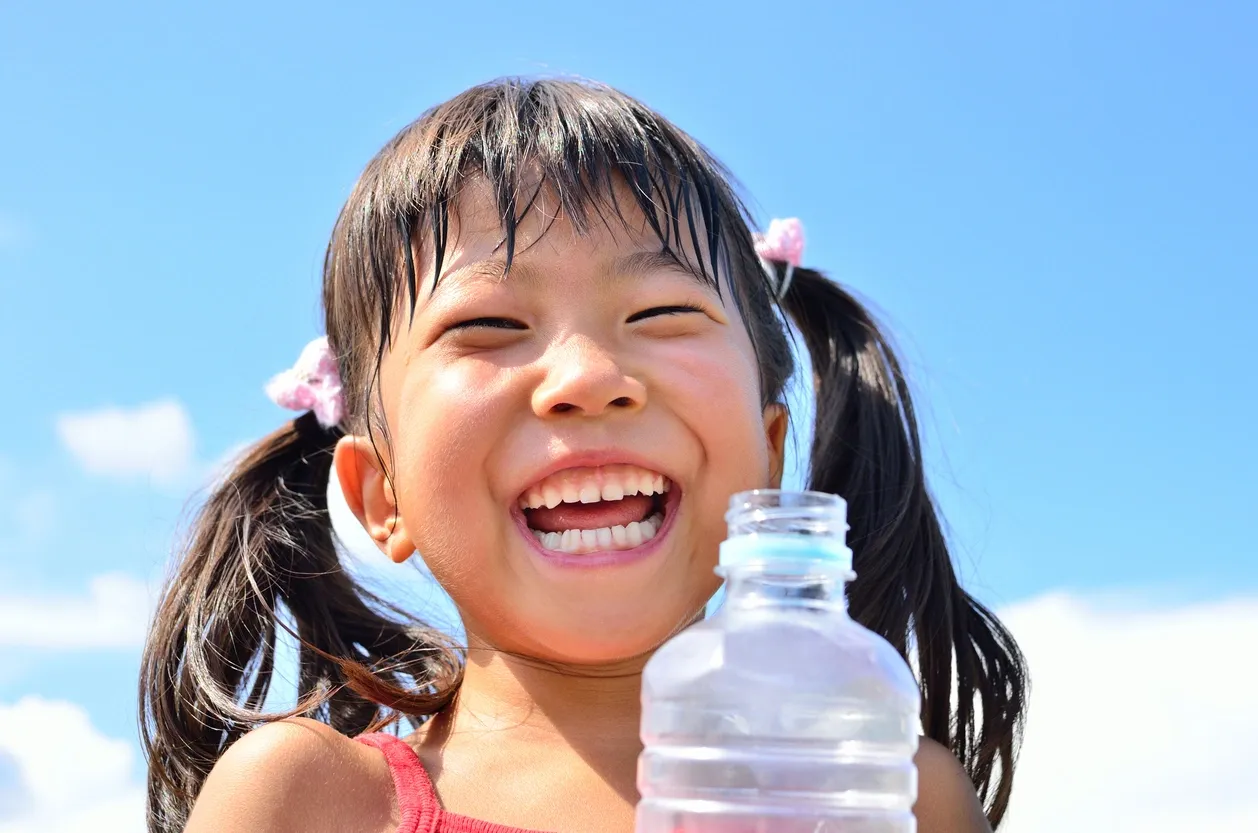 girl smiling holding a water bottle in her hands